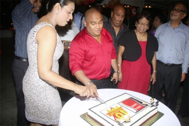 John Lewis and his wife cutting the cake as they celebrate their company’s 10th year anniversary. (Photo by Arian Browne) 