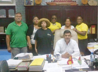 Deal sealed: Members of the GWMO are seen with Managing Director of BK International Brian Tiwari, seated. The GWMO members are from left to right, Clarence Jones, an associate member, Roslyn Primus, US member Sonja Fiedtkou-Perry, Simona P Broomes, Dana Jones and President Simona Broomes.