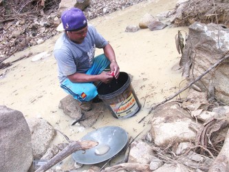 A miner uses a rag to squeeze out the mercury from the amalgam of gold and mercury at Isseneru last week.