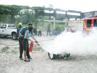 An AINLIM employee learning how to use the fire extinguisher 