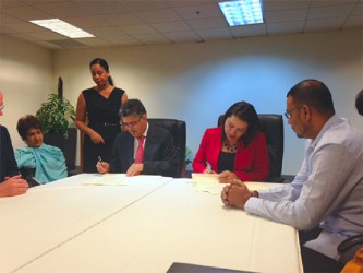 Minister of Foreign Affairs of Guyana Carolyn Rodrigues-Birkett (seated right) and Minister of External Affairs of Venezuela Elias Jaua Milano (seated left) in Port of Spain yesterday signing an agreement to explore mechanisms to address the issue of maritime delimitation within the context of international law. They agreed too that a technical team would meet in four months to exchange views on how that delimitation could proceed. Seated far right is Minister of Natural Resources and the Environment Robert Persaud. (Photo courtesy of Ministry of Foreign Affairs). 