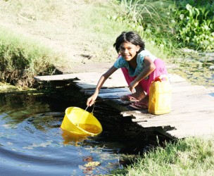 This young girl was fetching water from the  trench in front of her yard to complete her yard chores.