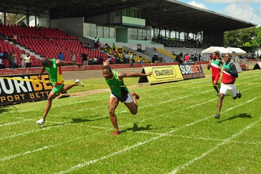 Kevin Abbensettes claiming a thrilling victory in a photo finish with Jason Yaw in the 200m yesterday. (Orlando Charles photo)