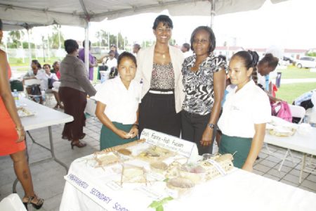 Two Paramakatoi students and their teacher pose with FAO’s Angela Alleyne (second from right) while displaying their cassava delight at the Convention Centre