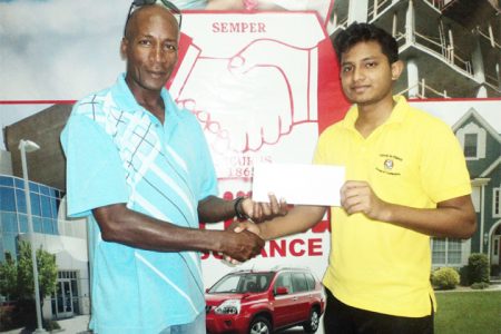 Coach of the Roberts Champions Boxing Gym, Jeff Roberts receiving the sponsorship cheque from Hand-in-Hand’s representative, Mark Samaroo yesterday. 