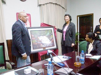 Parliamentary gift: Speaker of the National Assembly Raphael Trotman hands over a painting of Marshall Falls to Speaker of the Surinamese Parliament Dr. Jennifer Geerlings-Simons at Public Buildings yesterday. 