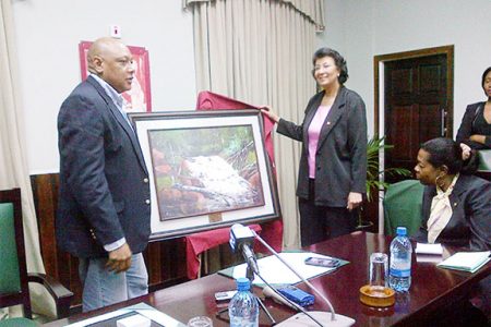 Parliamentary gift: Speaker of the National Assembly Raphael Trotman hands over a painting of Marshall Falls to Speaker of the Surinamese Parliament Dr. Jennifer Geerlings-Simons at Public Buildings yesterday. 