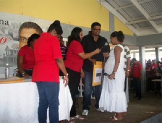 Minister of Housing and Water Irfaan Ali helps one of the prospective awardees to pull her house lot number for the Lust-en-Rust Housing Scheme (GINA photo) 