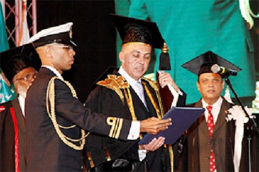 Aide-de-camp to the President, Lieut Commander Don Polo, left, assists President Anthony Carmona as he takes the Chancellor’s Oath during the installation of UTT’s chancellor at the O’Meara Campus. Looking on at right is Tertiary Education Minister Fazil Karim. 