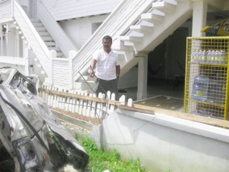 Satya Bissoon points to a section of his broken fence (David Papannah photo)