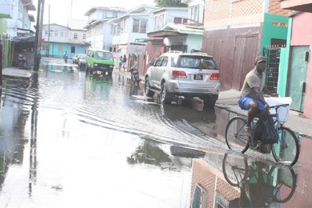 A cyclist pedals through flooded streets of Albouystown.
