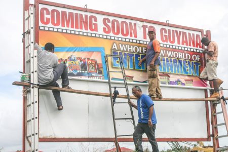 A sign going up today for MovieTowne at its construction site Turkeyen.
