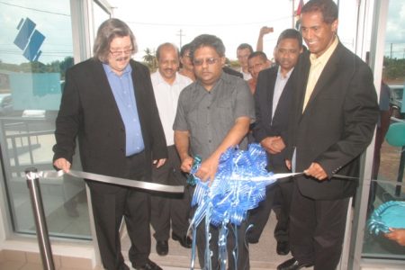 Minister of Finance Dr Ashni Singh cutting the ribbon. He is flanked by John Alves (left) and Nigel Baptiste. (GINA photo)
