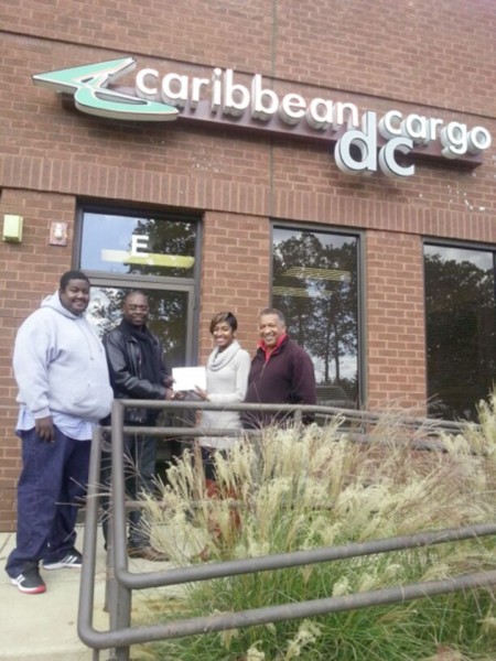 In picture from L - R are as follows: Customer Representative Earl “Sleepy” Paul,  Aubrey “Shanghai” Major, Marketing Representative  Tenisha DeSouza handing over the undisclosed sum to Major and CEO of Caribbean Cargo DC. Royston DeSouza. 