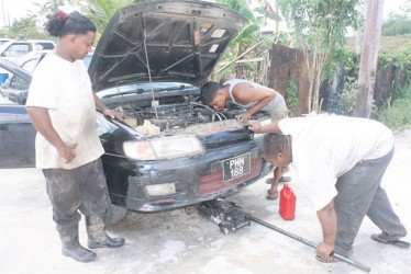Ramesh Kishun at the workshop with workmates fixing a car