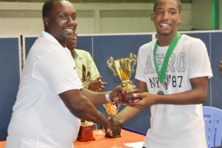 Queen’s College student Shemar Britton is continuing his excellent showing in local table tennis. Not content with being one of the youngest players to ever win a men’s singles competition, the talented junior player on Sunday led Queen’s College to the U18 team title in the annual Digicel sponsored Schools team and individual championships. He then returned the next day to win the U18 singles defeating Elishaba Johnson in the final. As expected Britton was voted the most outstanding male player of the tournament.  In the photo above, Britton, right receives his MVP award from Digicel’s Sponsorship and Events manager Gavin Hope.