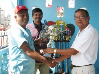  Clifton Phillips (R) hands over the trophies to BVA President Gregory Rambarran in the presence of Rollers Club President, Tony Rambarran. 