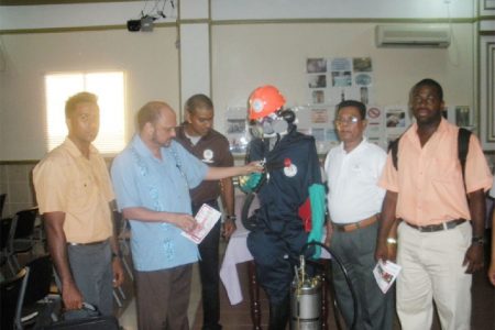 Minister of Health Dr Bheri Ramsaran (second from left) inspects one of the safety suits used by the VCS. In photo from left to right are Dr. Ahmad, VCS director Reyaud Rahman, VCS Chief Inspector Karanchand Krishnalall, and Dr. Dos Santos.