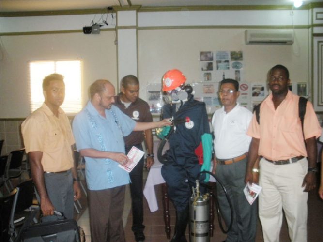 Minister of Health Dr Bheri Ramsaran (second from left) inspects one of the safety suits used by the VCS. In photo from left to right are Dr. Ahmad, VCS director Reyaud Rahman, VCS Chief Inspector Karanchand Krishnalall, and Dr. Dos Santos.
