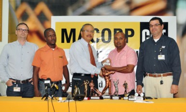 MACORP representatives Jordi Pinol, Damien Lewis (first and second from left) flank CEO Jorge Medina as he hands over the trophies to Lusignan Club Vice-President Dave Mohamed. MACORP Mining Major Accounts Manager Angel Rueda is pictured at right.  