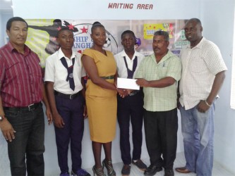 General Manager of the Bushy Park Sawmills, Patty Ramlall (second from right) hands over the sponsorship cheque to teacher and coach of the Uitvlugt Secondary School, Chevon Monchoir as students of the institution and co-founders of the K&S Organization, Kashif Muhammad (left) and Aubrey ‘Shanghai’ Major(right)  look on.