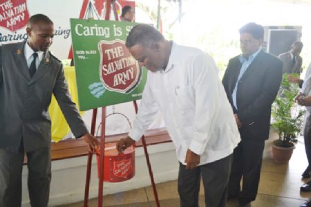 Prime Minister Samuel Hinds contributing to the Salvation Army’s Christmas Kettle. The Salvation Army received $5 million from the Government of Guyana yesterday at the launch of its Christmas Appeal at the Georgetown Club on Camp Street. (Government Information Agency photo)
