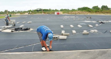  Workers laying the synthetic material on the track at the Leonora facility. (Orlando Charles photo)   