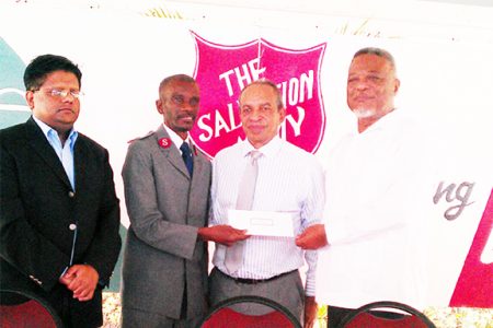 Prime Minister Samuel Hinds (right) handing over a cheque to Major Emmerson Cumberbatch of the Salvation Army at the launch of its Christmas Appeal 2013