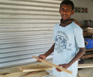 Tariq Albert holds up a piece of wood he just cut