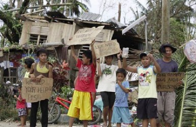 Children hold signs asking for help and food along the highway, after Typhoon Haiyan hit Tabogon town in Cebu Province, central Philippines November 11, 2013. (Reuters/Charlie Saceda)