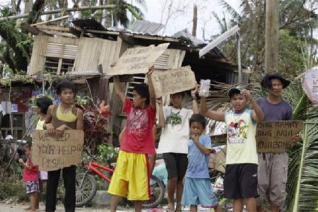 Children hold signs asking for help and food along the highway, after Typhoon Haiyan hit Tabogon town in Cebu Province, central Philippines November 11, 2013. (Reuters/Charlie Saceda)