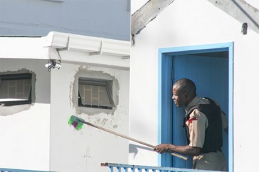 A policeman using a broom in an attempt to knock out cameras which the shooter was using to check the location of the cops.