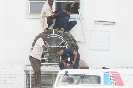 A medical staffer of the Dr Balwant Singh Hospital being rescued by police from a building next to the scene of the shooting. In the photo below a second staffer is being helped to safety.