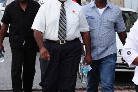 Journalist Sanka Price  (left front)  and Editor-in-Chief Roy Morris (left background) as they were led to the Magistrates’ court.