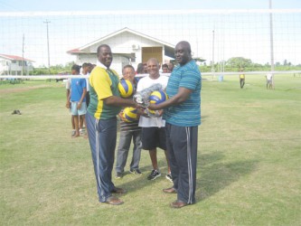BVA Secretary Levi Nedd presents volleyball gear to Skeldon Back Centre’s Linden Murray while Clifton Phillips (background, left) and Gregory Rambarran (right) look on.  