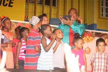 Prime Minister Samuel Hinds, holding the Samsung tablet used to light the Christmas tree, Mrs Hinds, close beside him, their grandson, first from right and children from the audience preparing to light the Christmas tree. 