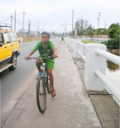 A lad rides his bicycle along the  public road in Land of Canaan.   