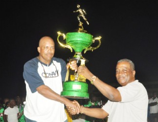 Chief-of-Staff of the GDF Brigadier Mark Phillips hands over the wining trophy to a representative of the winning Guyana Police Force team. (Orlando Charles photo) 
