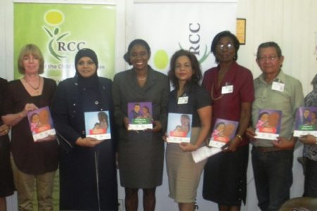 Minister of Human Services and Social Security Jennifer Webster (fourth, left) displays the child-friendly versions of the acts with RCC Chairperson Aleema Nasir (third, left), UNICEF representative Marianne Flach (second, left), and members of the RCC.