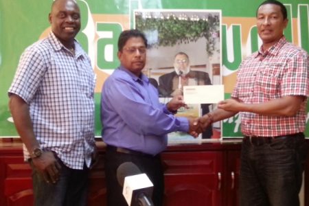 General Manager of Bakewell, Rajendranauth Ganga hands over the sponsorship cheque to co- founder of the K&S Organization, Kashif Muhammad while his business partner, Aubrey ‘Shanghai’ Major looks on. 
