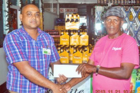 Coach Randolph Roberts of the Flying Ace Cycle Club of Berbice collects the sponsorship cheque from Banks DIH Limited Berbice Sales Manager Joshua Torrezao