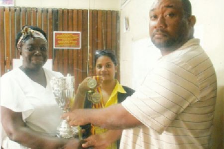 RHTYSC Secretary/CEO Hilbert Foster (right) presents a number of medals to New Amsterdam School Deputy Head Teacher Shondell Phillips (left) for its annual graduation ceremony as another staff member looks on. 
