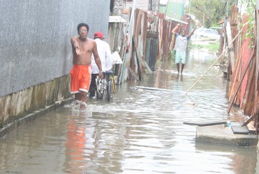 A James Street, Albouystown man showing Stabroek News the level of water they still have to navigate in an alleyway.