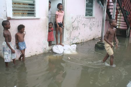 A Hill Street, Albouystown family surrounded by floodwater.