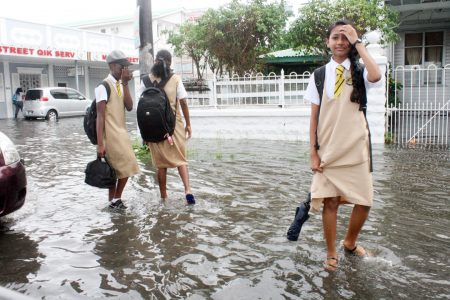 Students walking past the flooded Ministry of Culture on Main Street yesterday