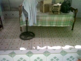 A bed and a fan in the floodwaters at the bottom flat of Devika Persaud’s home 