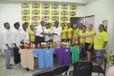 Guyana Beverage Company Incorporated president Robert Selman presents a cheque to the President of the Enterprise Busta Sports Club, Karran Ramdhoon while Busta representatives and club officials look on. 