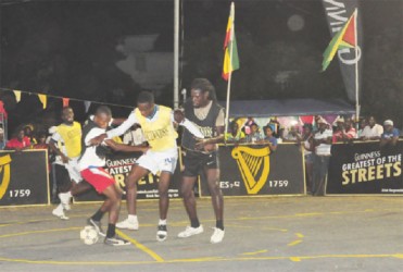 Leopold Street’s Okeene Fraser (second from right) battling to keep possession of the ball sandwiched between two Castello Housing Scheme players. 