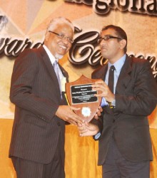 Nigel Harris presenting Anna Regina Secondary School Principal Lalljeet Ruplall receiving the 2013 CSEC school of the year award