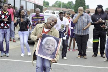 People sing and dance during a gathering of mourners on Vilakazi Street in Soweto, where the former South African President Nelson Mandela resided when he lived in the township, December 6, 2013. REUTERS/Ihsaan Haffejee
